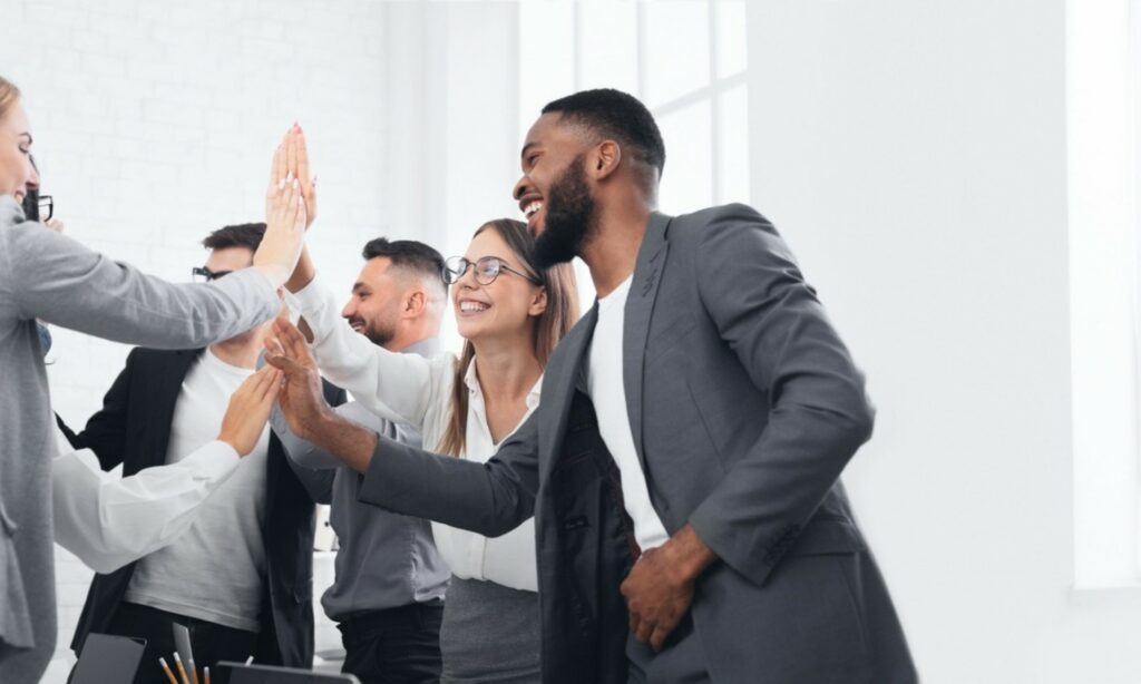 Equipo de trabajo celebrando con las manos en alto